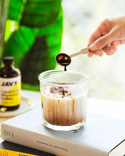 Dropping coffee concentrate into iced coffee.